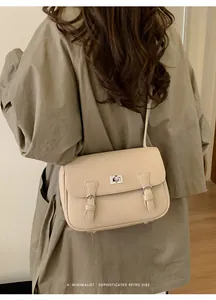 Detailed back view of a beige lychee pattern leather shoulder bag on a trench coat