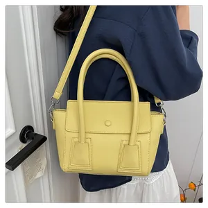Détail d'un sac à main jaune vif à motif litchi avec deux poignées et une bandoulière