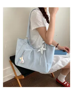 Detail of light blue polka dot tote bag with star charm and plush rabbit on model