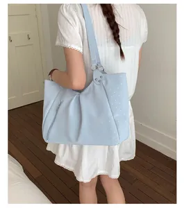 Detailed view of light blue polka dot tote bag, showing shoulder strap and side zipper.