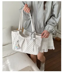 Detailed shot of white polka dot tote bag featuring silver star and bunny charms