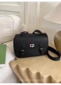 Detail of black pebbled leather texture and silver rectangular twist-lock on retro bag