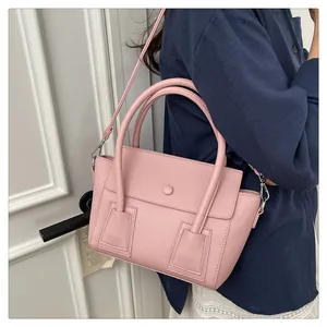 Sac à main rose texture litchi porté par un mannequin avec bandoulière réglable