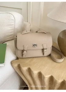 Detail of lychee pattern beige messenger bag with silver twist lock on wood stool