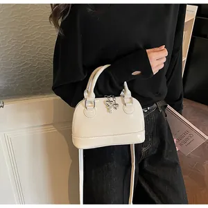 Détail du sac à main blanc avec pendentif cœur en argent et finition laquée brillante