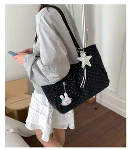 Detail of black polka dot canvas tote bag with rabbit charm and wide shoulder strap