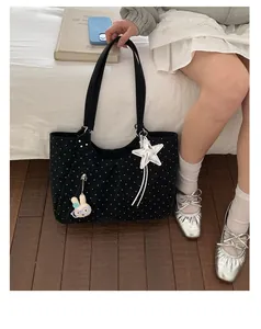 Detail of black polka dot tote bag featuring silver star and cute bunny doll charms