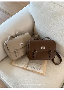 Detail of retro litchi grain square bags with silver metal locks on a white sofa