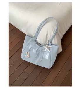Light blue polka dot tote bag with star charm and bunny keychain on a cozy bed.
