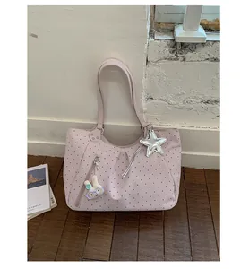 Detail of a stylish pink polka dot tote bag featuring cute rabbit and silver star charms