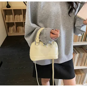 Close-up of a cream shell-shaped handbag with silver heart and key charm accents