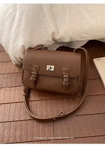 Detail of brown lychee grain leather crossbody bag with silver twist lock and retro vibe
