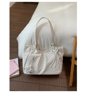 Detailed view of the white polka dot tote bag featuring silver star and rabbit charms.