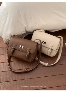 Detailed view of retro litchi grain texture and metal buckle on brown and cream crossbody bags