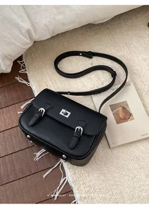 Detail view of black pebble leather mini satchel with silver twist lock and bottom metal feet