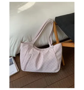 Detailed view of a pink polka dot tote bag in a cozy lifestyle setting with shoulder straps.