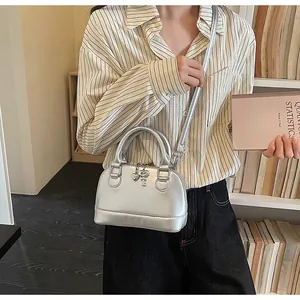 Mini sac à main argenté métallisé avec breloques cœur et clé porté par un mannequin