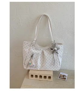 Detail of a white polka dot tote bag with cute star and bunny charms on a brick stand.