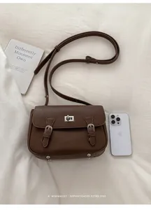 Detailed view of brown lychee leather crossbody bag with silver hardware and turn-lock