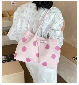 Dettaglio della borsa tote rosa chiaro a pois magenta con fibbia e tracolla sottile