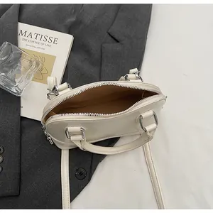 Détail du sac à main beige montrant le compartiment intérieur et la fermeture éclair argentée