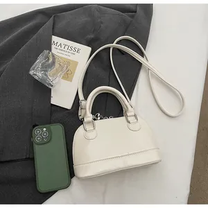 Sac coquille crème chic avec détails argentés sur fond de blazer gris élégant