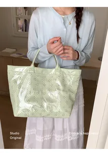 Détail d'un sac cabas vert menthe ajouré avec motifs floraux et texte imprimé
