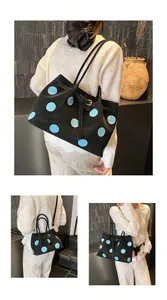Dettaglio della borsa tote nera a pois con trama opaca e fibbia decorativa in metallo