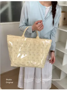 Close-up of pale yellow tote bag featuring laser-cut floral patterns and glossy texture