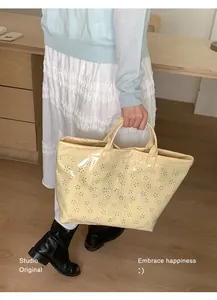 Gros plan du sac cabas crème avec motifs floraux découpés au laser et texte