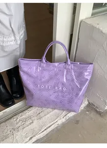 Detailansicht der lila glänzenden Tragetasche mit Blumenmuster und weißem Logo