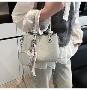 Detalle de bolso bucket en cuero gris con asa anudada y monedero circular a juego