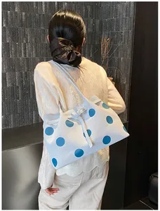 Grande borsa tote celeste a pois blu scuro indossata da una modella per un look da ufficio