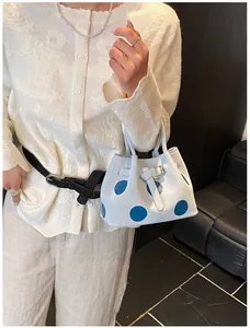 Dettaglio della borsa tote azzurra a pois con fibbia in metallo e texture opaca sul modello