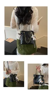 Detail of black quilted bucket bag with chain strap and horse charm shown on a model