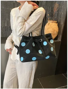 Borsa tote grande con pois indossata da una modella su uno sfondo grigio materico