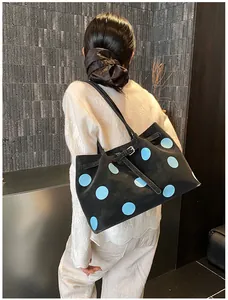 Dettaglio laterale di borsa tote con grandi pois blu su tessuto nero opaco elegante