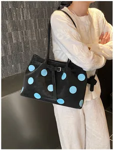 Borsa tote grande nera a pois blu portata a spalla da una modella, vista laterale