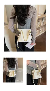 Detailed close-up of a white quilted bucket bag with gold chain and small horse charm