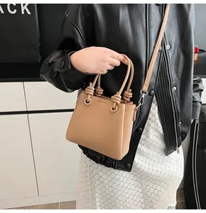Sac seau en cuir grainé marron avec détail de nœud à la main porté par un mannequin