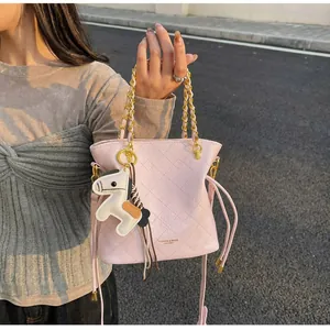Detail of light pink quilted bucket bag with gold chain strap and horse charm