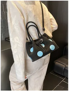 Dettaglio borsa a secchiello nera a pois con fibbia argento e tracolla rimovibile