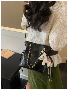 Detail of black quilted tote bag with gold chain strap and cute white pony charm accessory