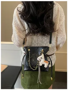 Detail of black quilted leather tote with gold chain strap and horse charm decoration
