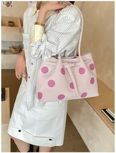 Borsa a secchiello rosa a pois con fibbia argentata indossata da una modella in interno