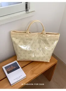 Détail du sac cabas crème avec motif floral ajouré et finition imperméable brillante