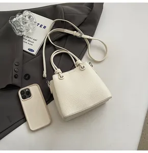 Détails de la texture grainée et de l'anse nouée sur le sac à bandoulière beige