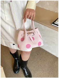 Dettaglio della borsa tote rosa a pois con fibbia decorativa e doppi manici superiori