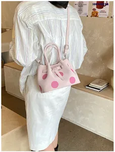 Borsa a secchiello rosa a pois in un ambiente lifestyle con tracolla regolabile