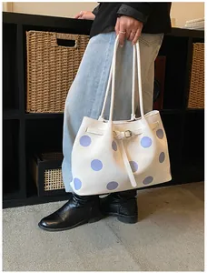 Dettaglio di una borsa shopper bianca a pois viola con fibbia decorativa in metallo